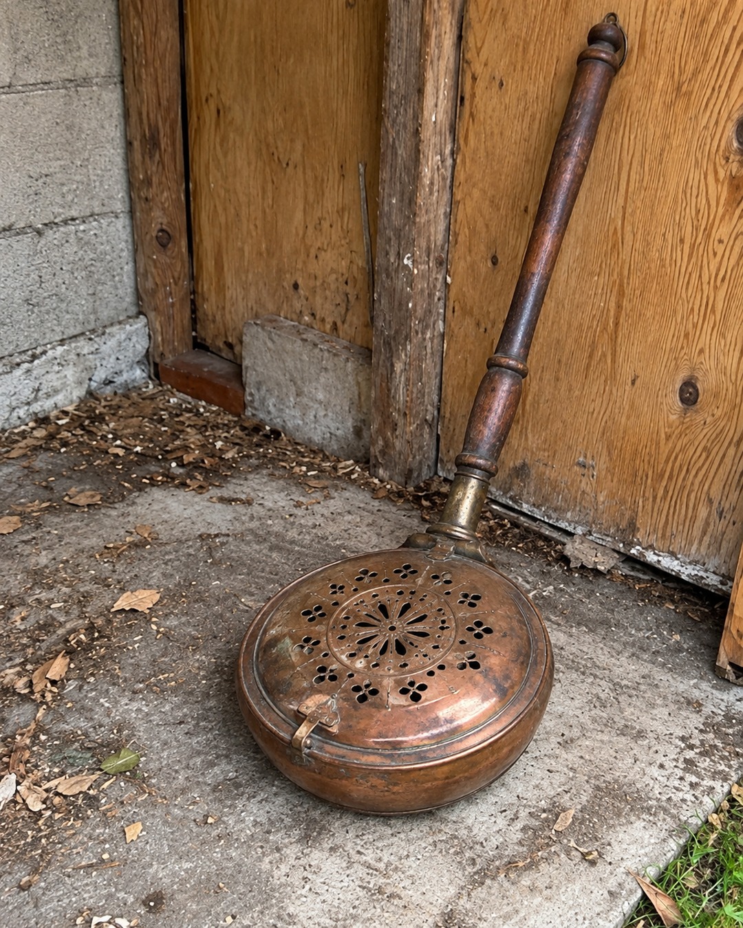 Antiguo calentador de cama de cobre con tapa calada y mango largo de madera